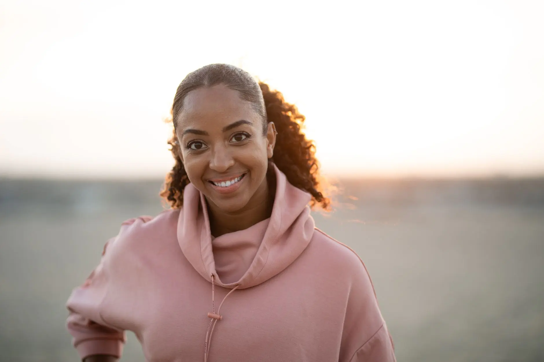 A woman smiling warmly in golden evening light