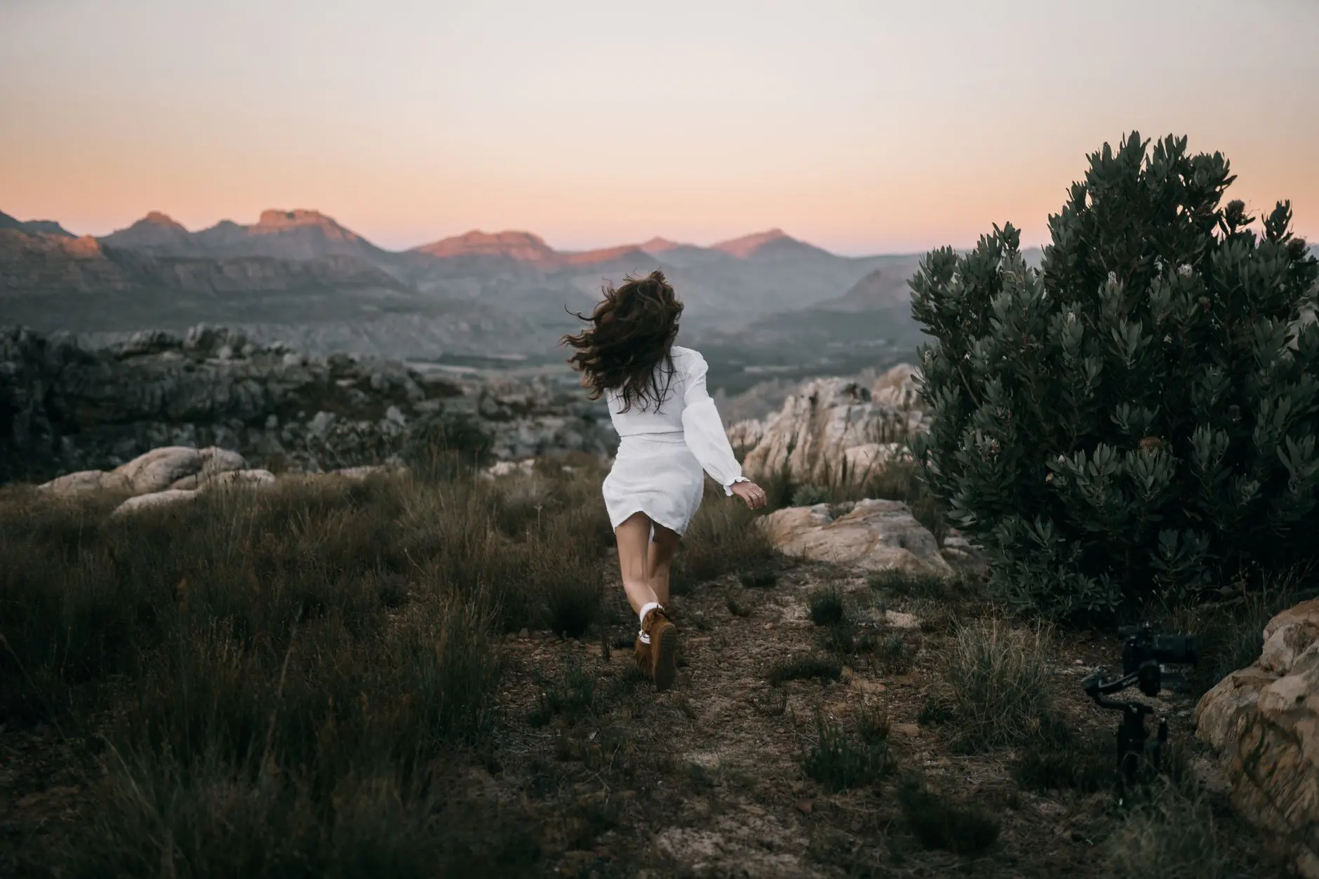 A woman running through the mountains at sunset