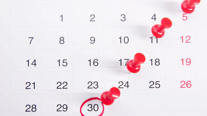 A calendar with red pins marking days and the 30th circled