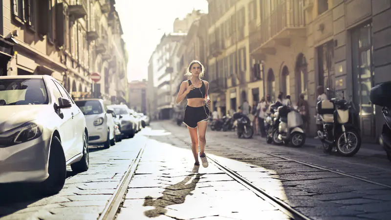 A woman jogging down a sunny city street