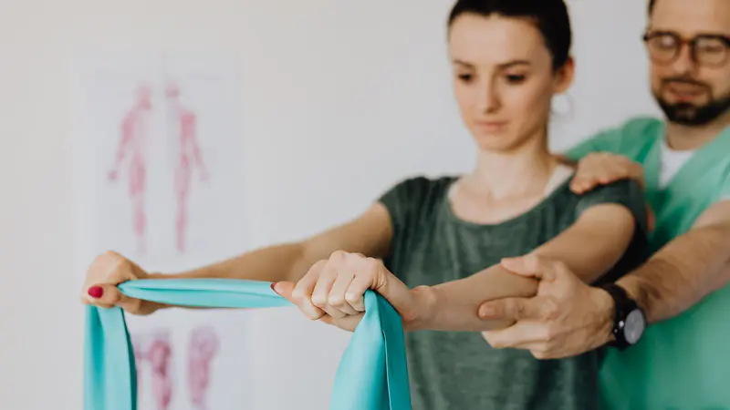 A physiotherapist guiding a woman through a resistance band exercise