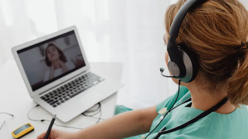 Health professional with a headset on a video call with a client
