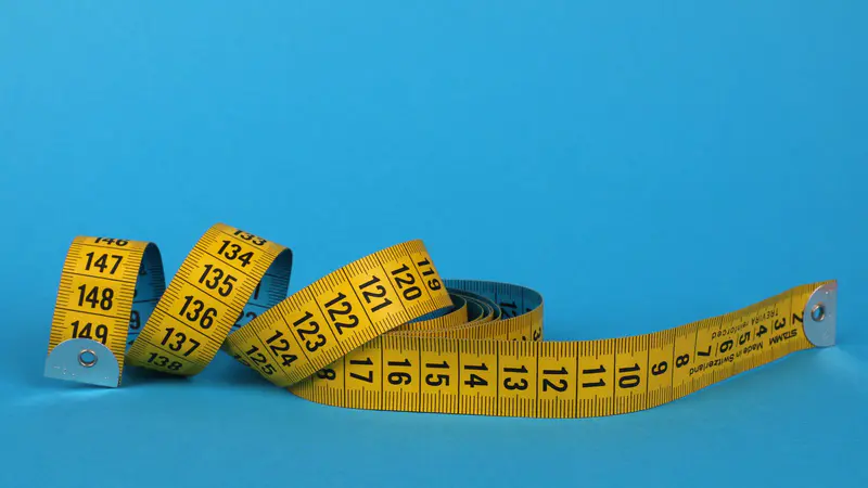 A yellow tape measure on a blue background