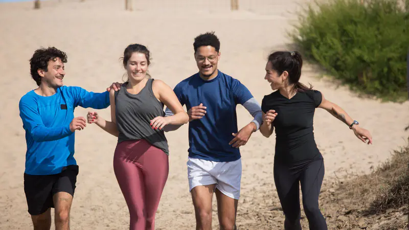 A group of friends running together on a sandy path
