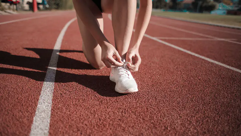 A woman tying her trainers on a running track