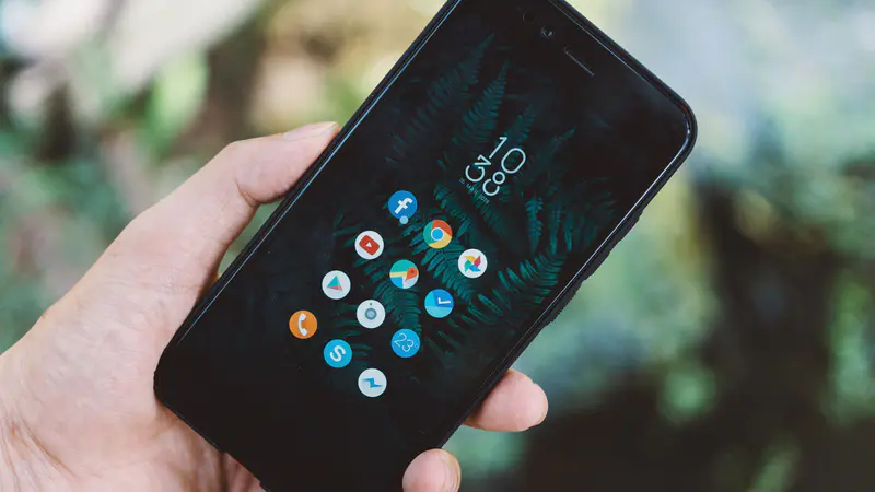 A hand holding a smartphone with app icons on the screen