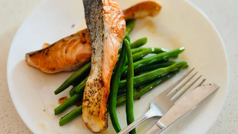 Grilled salmon fillet with green beans on a white plate