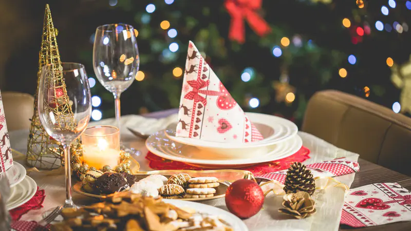 Christmas dinner table set with candles, festive napkins and biscuits