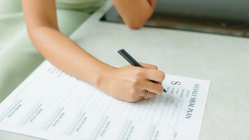 A woman filling in a weekly meal plan