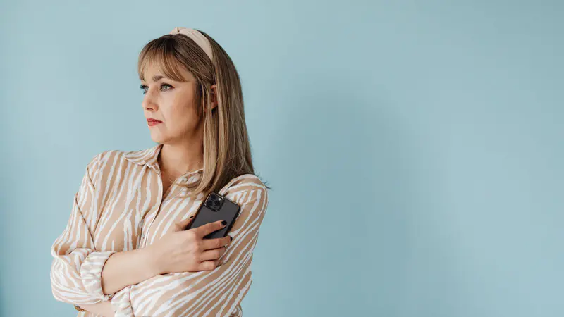 A thoughtful woman holding her phone