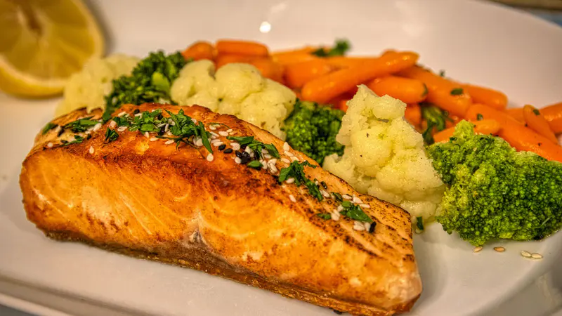 A salmon fillet served with broccoli, carrots and cauliflower