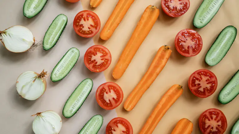 Sliced tomatoes, cucumbers, carrots and onions laid out on a table