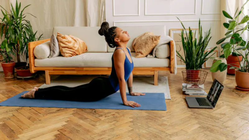 A woman following an online workout on her laptop at home