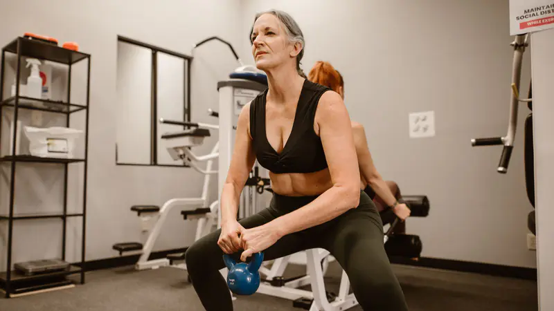 Woman doing a kettlebell squat in a gym