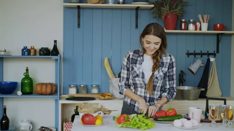 A young woman preparing a fresh salad in her kitchen