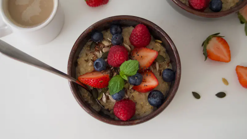 A bowl of oatmeal topped with berries and fruit