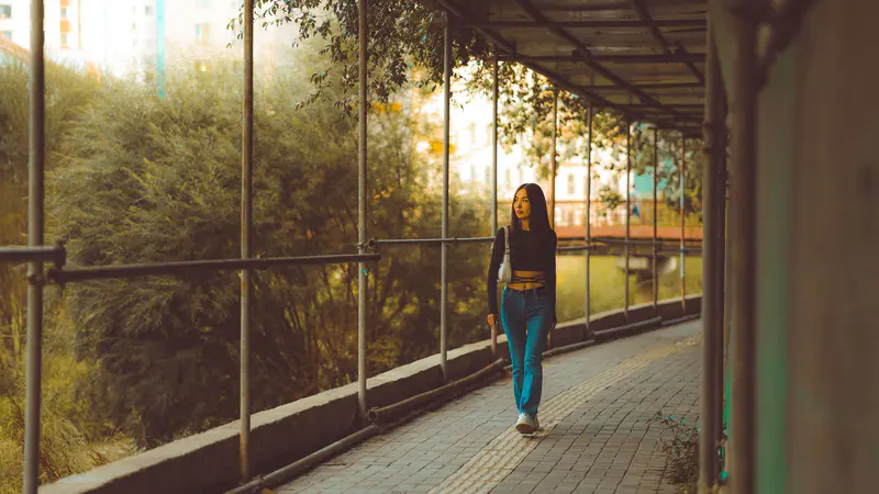 A woman walking along a leafy path at sunset