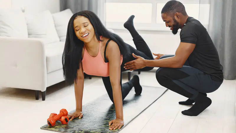 A coach helping a woman with an exercise at home