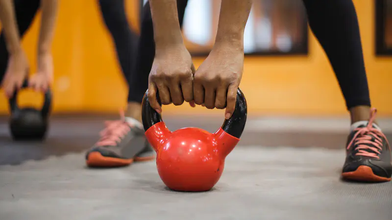 Hands gripping a red kettlebell before a lift