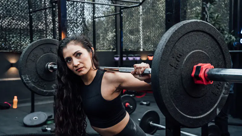 A woman setting up a loaded barbell in the gym