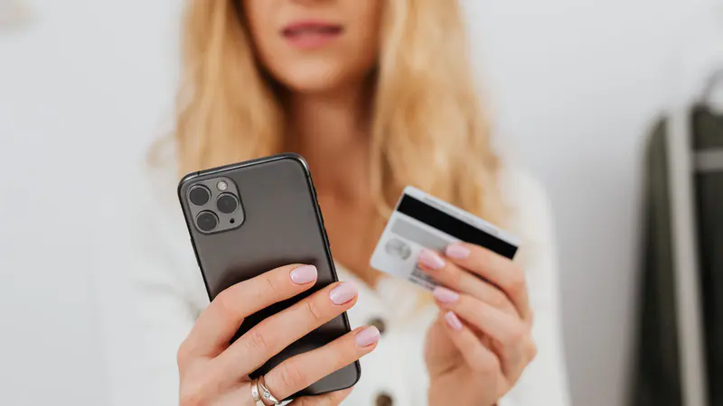 A woman holding a bank card and her phone
