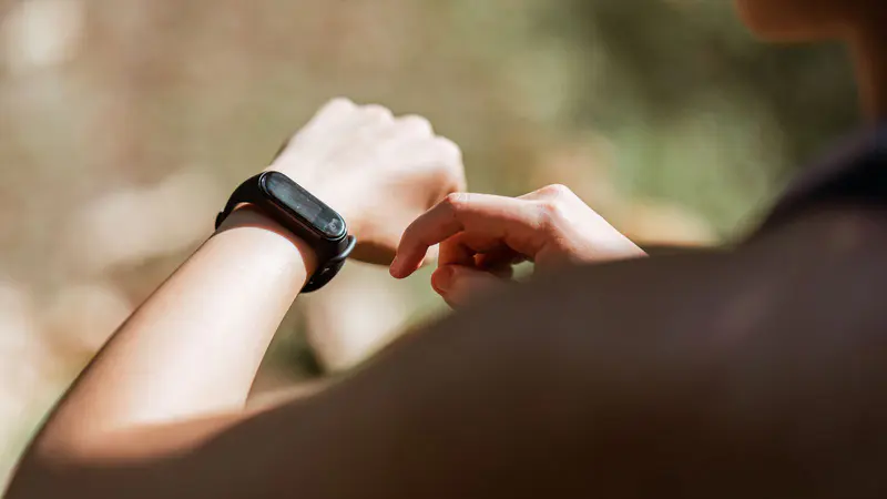 A woman checking the fitness tracker on her wrist outdoors