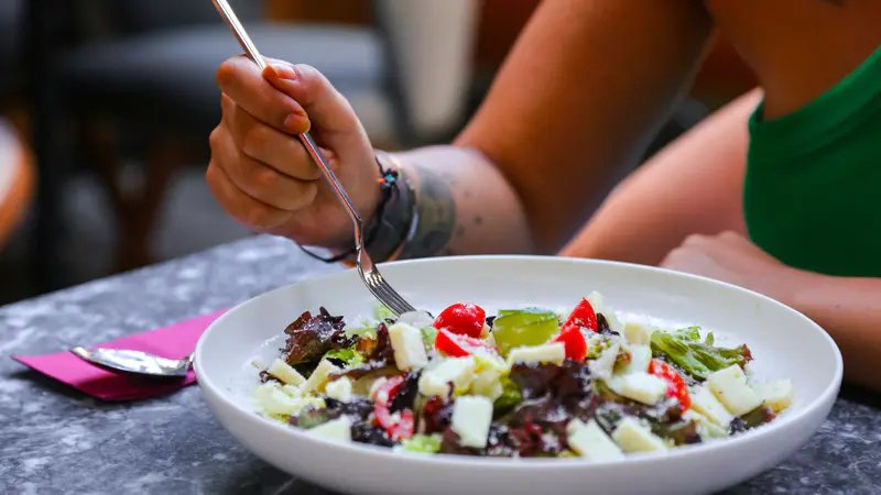 A fork over a colourful salad on a plate