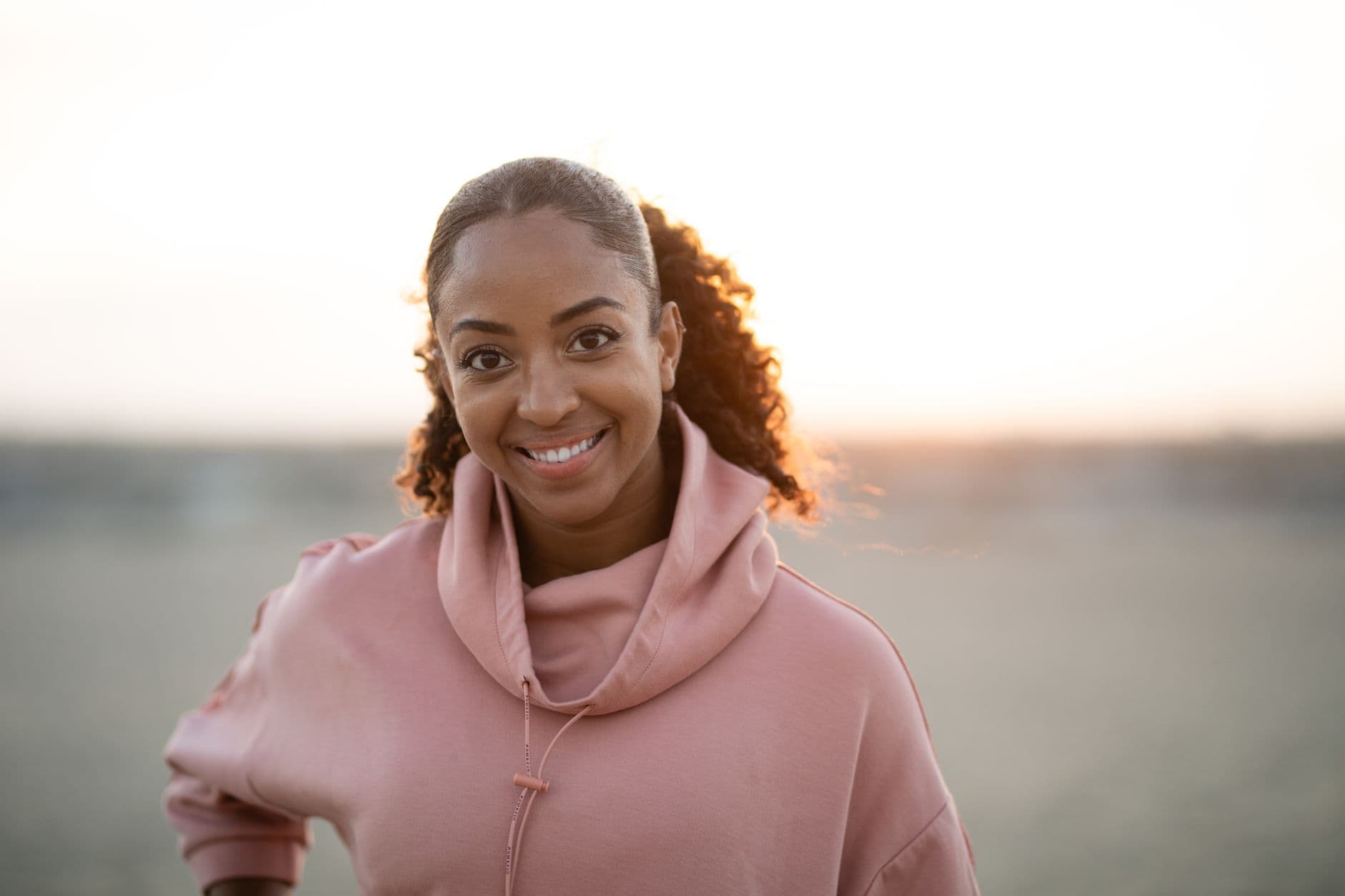 A woman smiling warmly in golden evening light